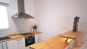 Une cuisine moderne avec des armoires blanches, un plan de travail en bois, un four encastré et une hotte de cuisine en acier inoxydable.