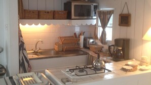 Uma cozinha com armários brancos, micro-ondas, fogão a gás e diversos utensílios.