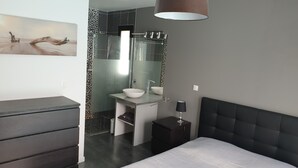 Een moderne badkamer met een glazen douche, een witte wastafel en een grote spiegel.