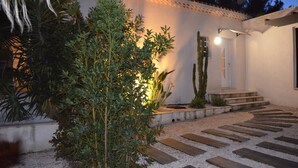 A well-maintained garden with a variety of plants and a wooden pathway leading to a building entrance.