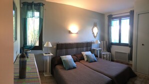 Een hotelkamer met twee bedden, een nachtkastje, een lamp, een spiegel en een raam met gordijnen.