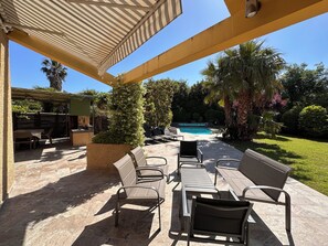 An outdoor patio with a pool, surrounded by greenery and furnished with chairs and a table. - Charming, luminous house with private swimming pool and pleasure garden (Laroque-Des-Albères)