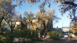 Edifici de pedra rústic envoltat d'arbres i un cotxe estacionat al davant.