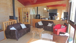 A cozy cabin interior with a fireplace, wooden furniture, and a large window.