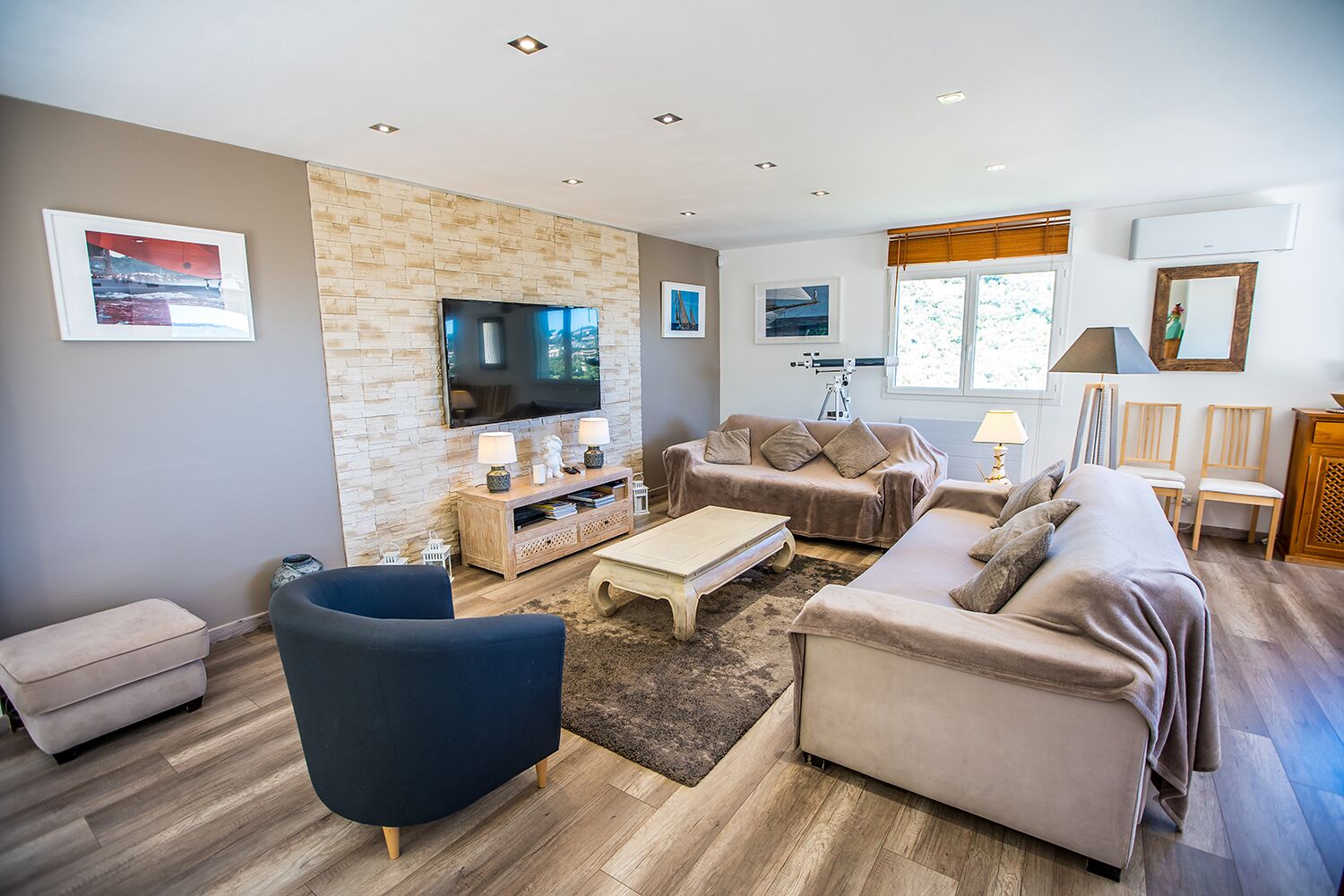 A modern living room with a stone wall, a flat-screen TV, a sofa, a coffee table, and a TV stand with lamps.