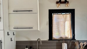 A modern kitchen with white cabinets, a stainless steel dishwasher, a sink, and a window with a curtain. - Le Nid des Baronnies: Rated 3-star vacation key! (Mirabel-Aux-Baronnies)