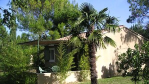 A house with a tiled roof, surrounded by greenery and a palm tree. - Le Nid des Baronnies: Rated 3-star vacation key! (Mirabel-Aux-Baronnies)