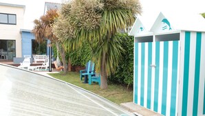 A beach house with a pool, a blue chair, and a striped beach hut. - Villa in Sainte Marine. heated pool. beaches, harbour, all on foot  (Combrit)