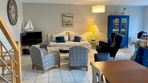 A living room with a sofa, two armchairs, a TV, a lamp, a bookshelf, and a clock on the wall. - Villa in Sainte Marine. heated pool. beaches, harbour, all on foot  (Combrit)