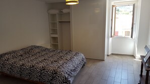 Une chambre à coucher avec une couvre-lit à motifs zébrés, une armoire blanche et une fenêtre donnant sur l’extérieur.