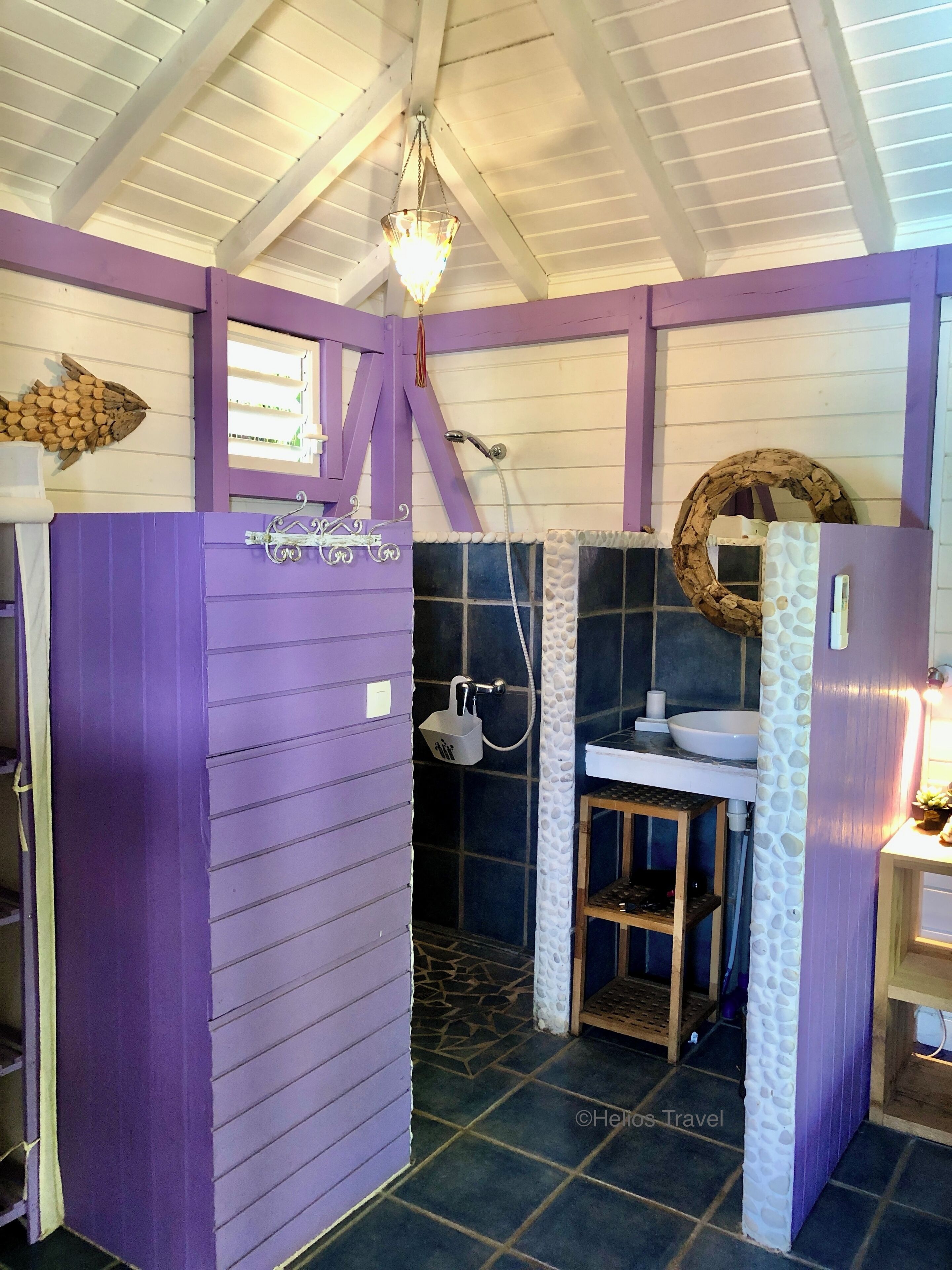 Une salle de bain avec une porte violette, une douche, un lavabo et un porte-serviettes.