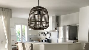 Et moderne køkken med en central ø, hvide skabe og et hængende lysarmatur.