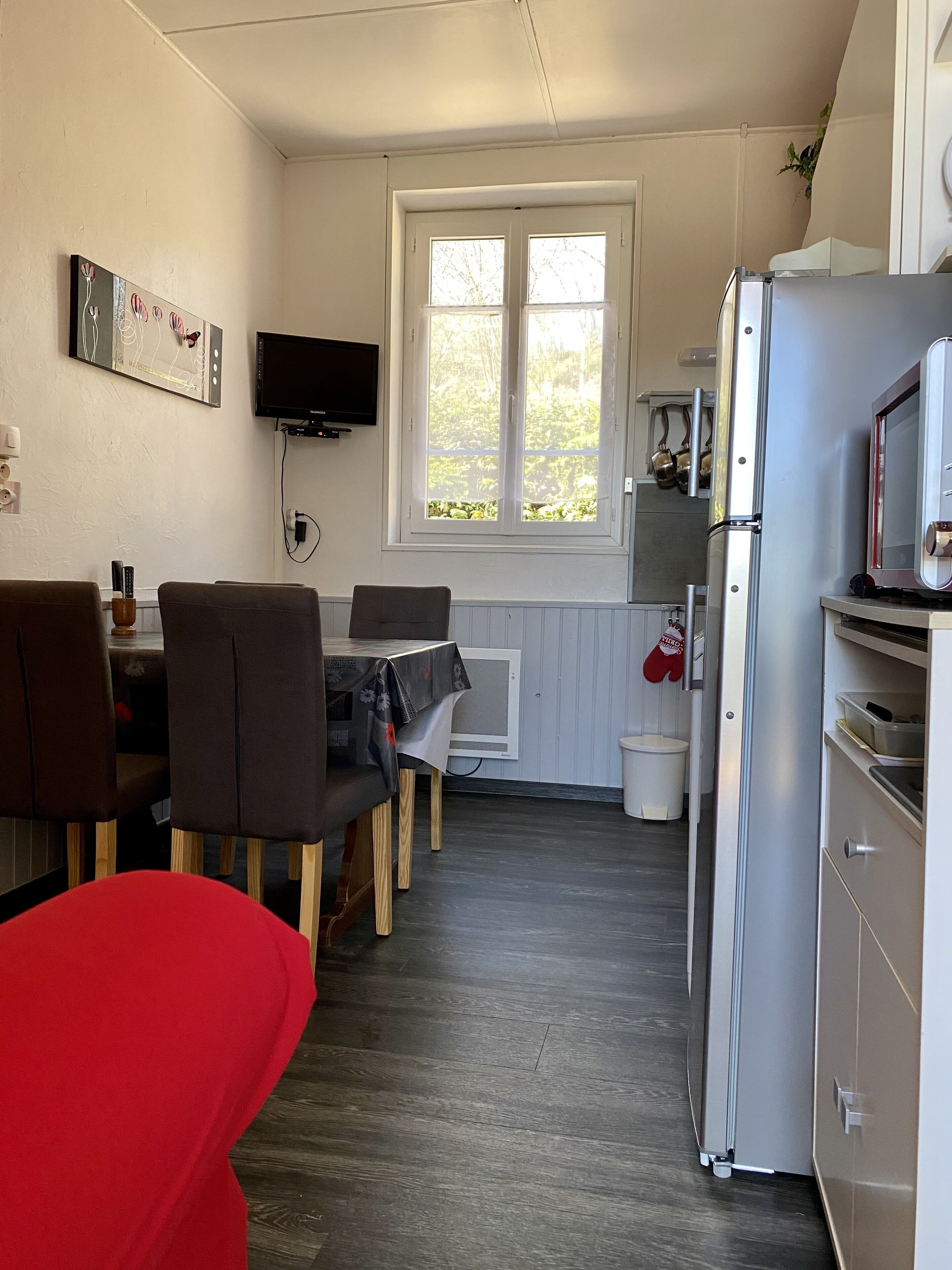 A compact kitchen with a dining area, a large window, and a built-in TV.