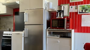 Une cuisine compacte équipée d’un réfrigérateur, d’une cuisinière, d’un four à micro-ondes et d’une machine à café.