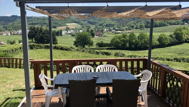 Une terrasse extérieure couverte, dotée d’une table et de chaises, qui offre une vue sur un paysage pittoresque.