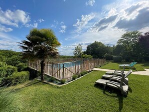 Un jardin bien entretenu, doté d’une piscine, de chaises longues et d’une clôture en bois.