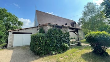 Une maison de plain-pied avec un toit en pente, une porte de garage blanche et une allée gravillonnée.