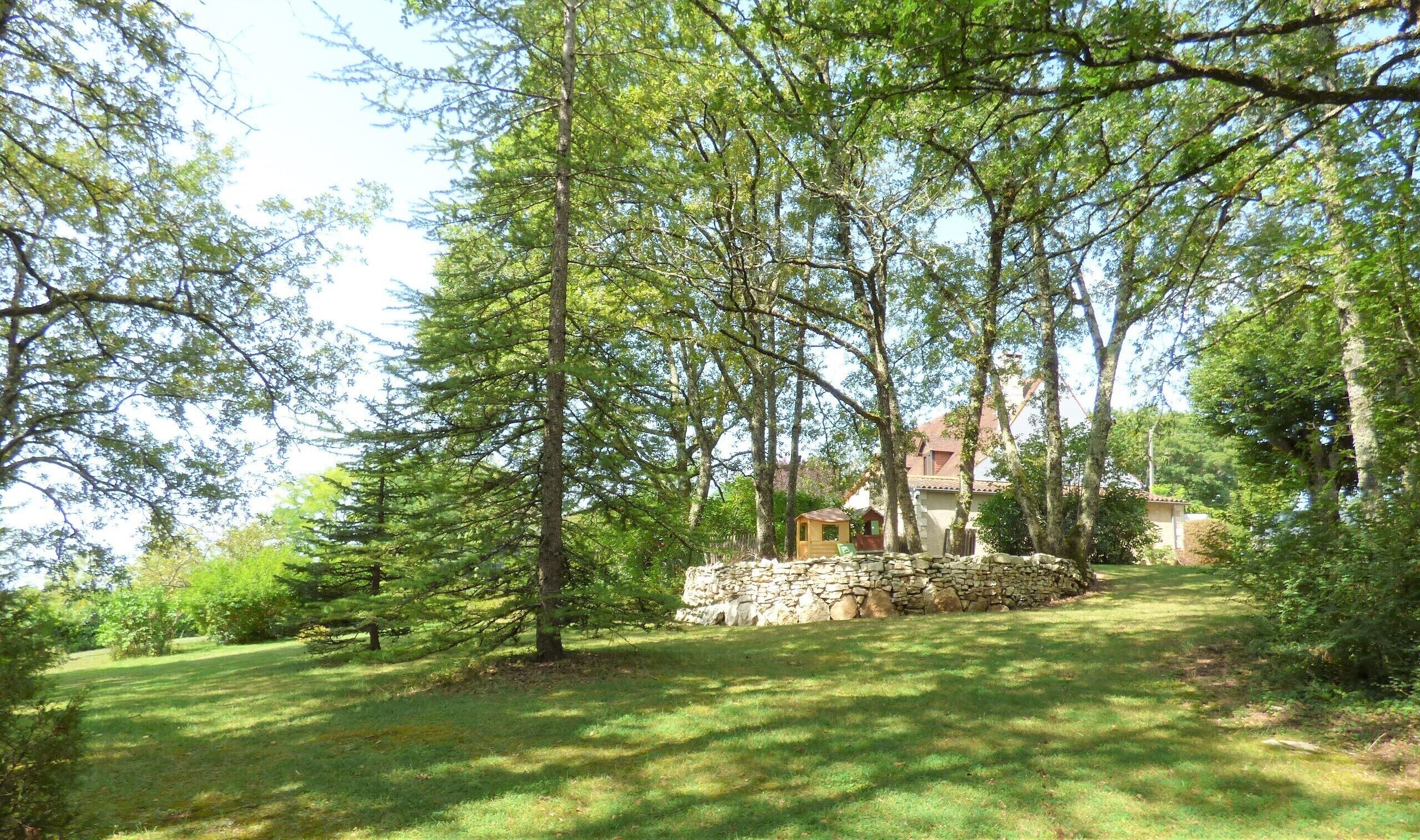 A stone house surrounded by trees in a grassy area.