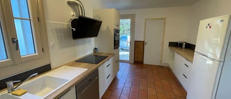 Una cocina equipada con lavavajillas, fregadero, estufa y refrigerador.