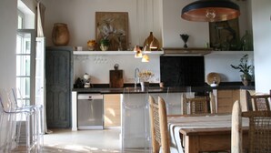 A modern kitchen with a wooden ceiling, clear glass chairs, and a dining table.