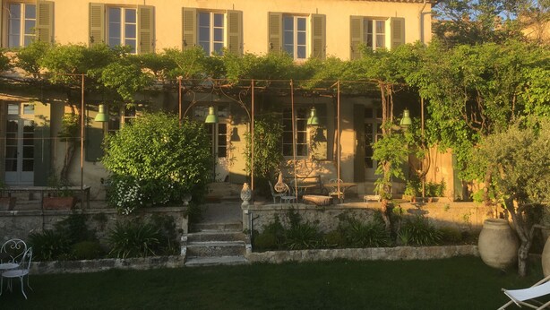 A traditional building with a covered patio, steps leading to the entrance, and outdoor seating.