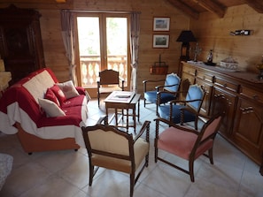 Um quarto acolhedor com decoração em madeira, com sofá, cadeiras, mesa e armário.