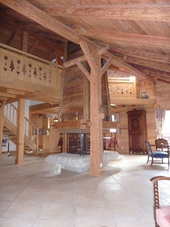 A spacious wooden interior with a high ceiling, a fireplace, and a staircase.