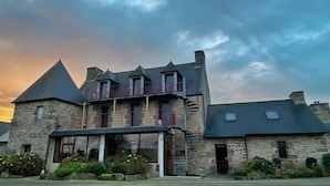 A stone building with a balcony, a spiral staircase, and a small attached structure. - Domaine de Kerzuat - Chambres d'hôtes (Plouarzel)
