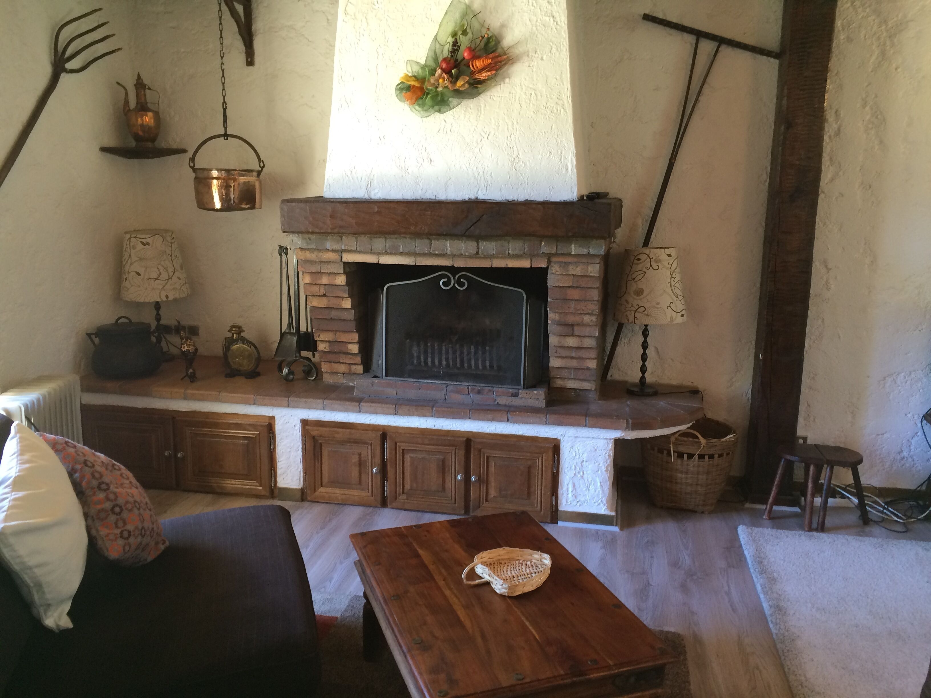 Ein rustikales Wohnzimmer mit Kamin aus Backstein, Holzmöbeln und gemütlicher Atmosphäre.