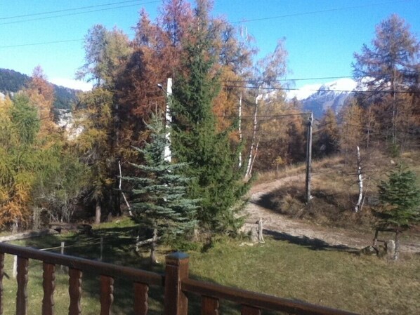 A wooden deck overlooking a mountainous landscape with autumn foliage and a clear sky. - Charming chalet close to the slopes in a small ski resort (Roubion)
