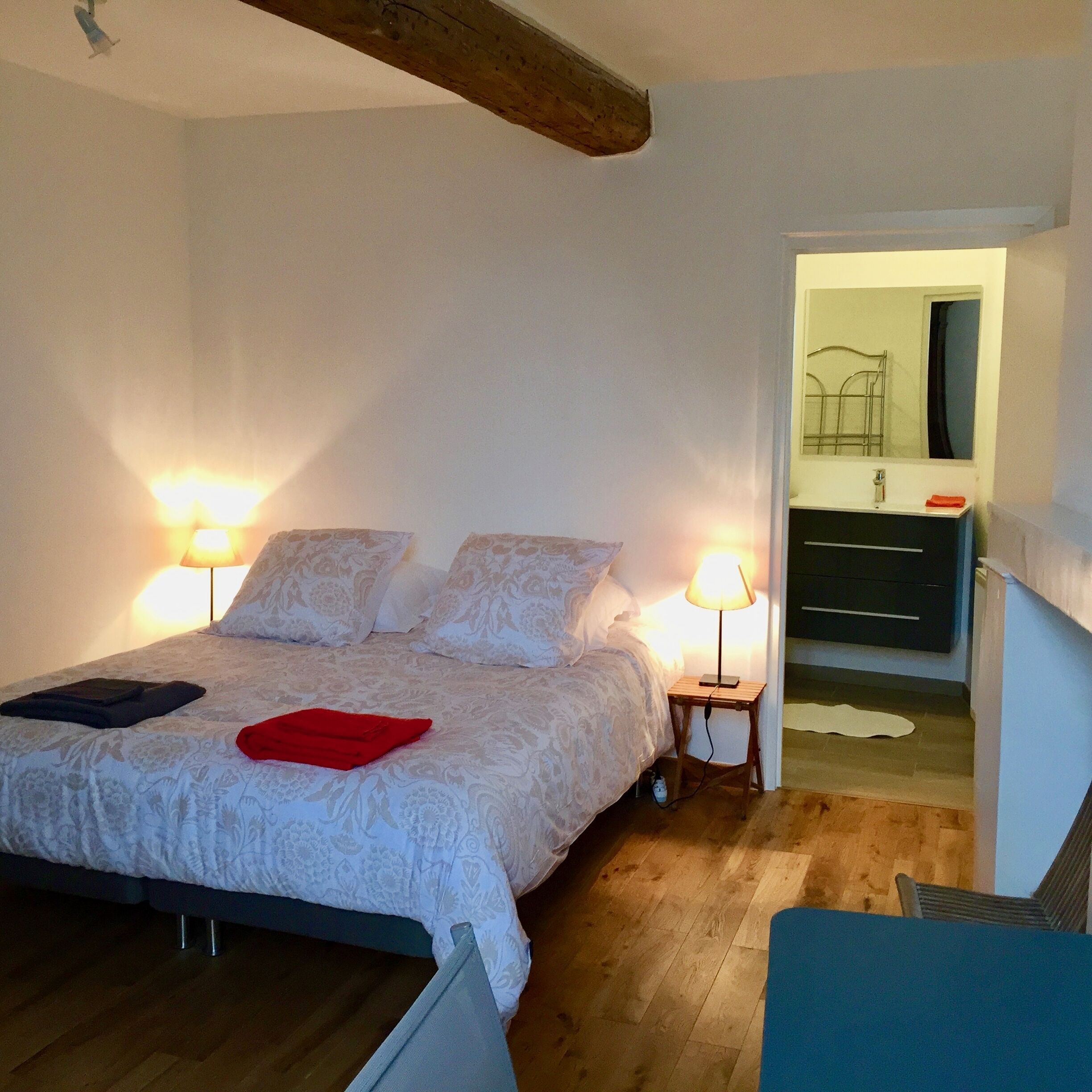 A bedroom with a bed, two bedside lamps, a dresser, and a mirror.