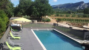 Une piscine rectangulaire dotée d’une terrasse en bois et de chaises longues.