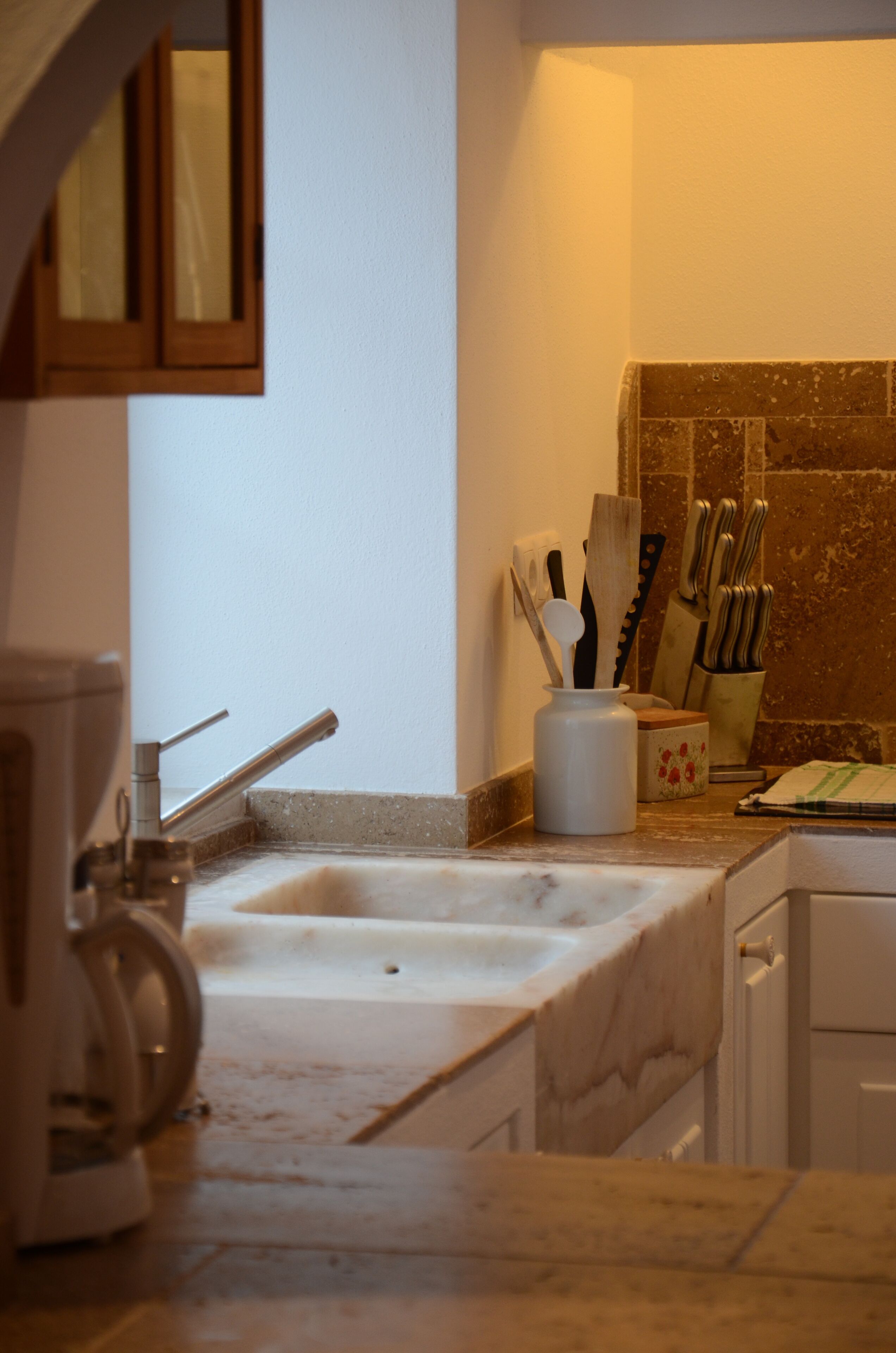 A kitchen with a marble countertop, a coffee maker, and a knife block.