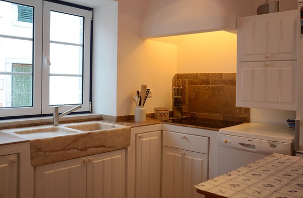 A kitchen with white cabinets, a sink, a dishwasher, and a window.