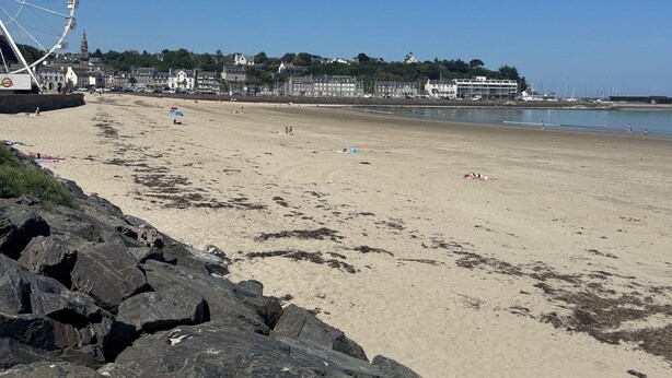 A beach with a large Ferris wheel, rocky shoreline, and buildings in the background. - Charming Studio Facing the Port and 100 m from the beach (Binic)