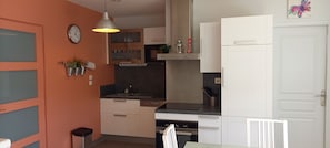 A modern kitchen with a clock, pendant light, and cabinets. - South-facing, cocooning gîte 40 m from the sea, rated 3***. (Fécamp)