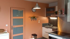 A modern kitchen with a round mirror, a clock, and potted plants on the wall. - South-facing, cocooning gîte 40 m from the sea, rated 3***. (Fécamp)