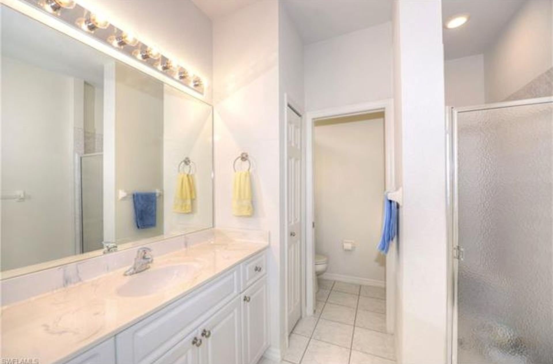 A bathroom with a large mirror, a sink, and a shower area.