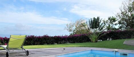 A swimming pool with a green chair and a tiled deck.