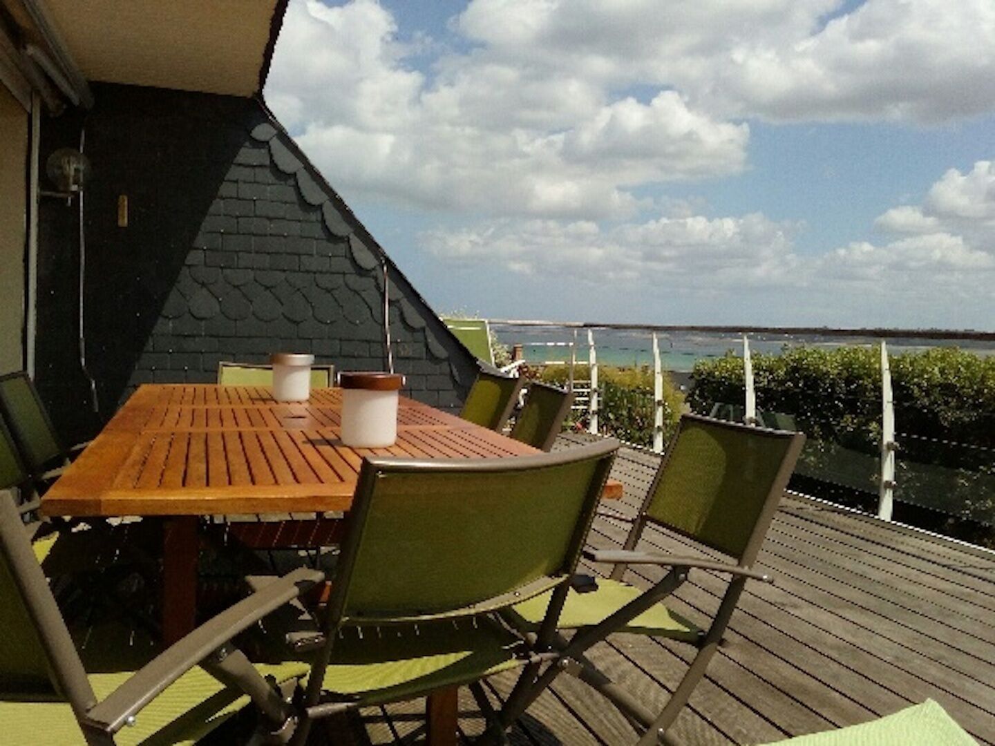 A wooden deck with a table and chairs, overlooking a body of water.