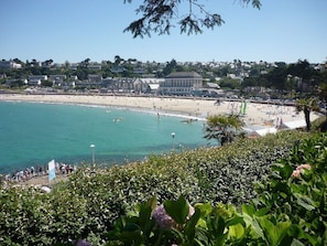 A coastal view with a beach, ocean, and buildings in the background.