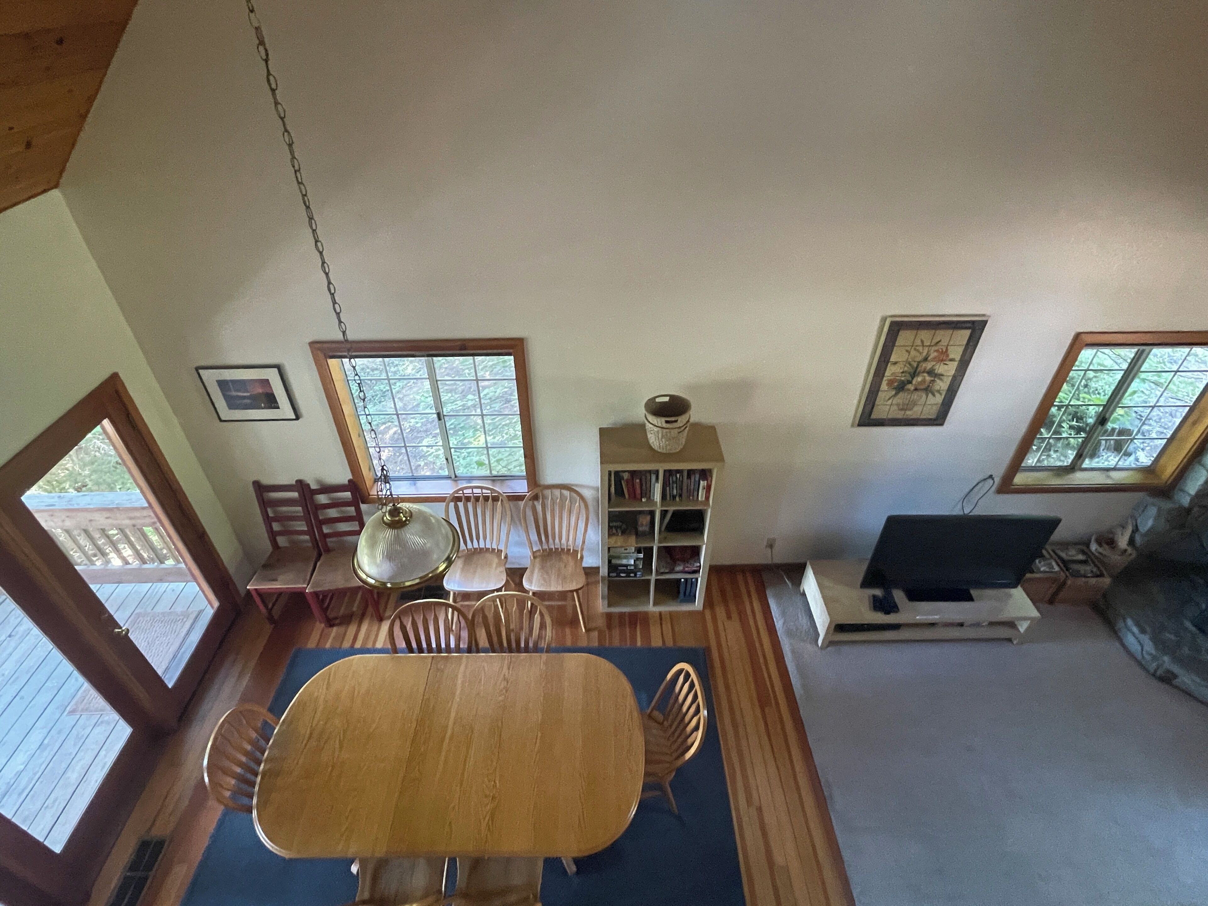 A dining area with a wooden table and chairs, a bookshelf, and a television.