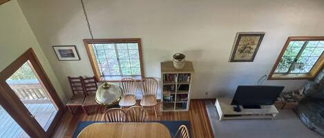 A dining area with a wooden table and chairs, a bookshelf, and a television.