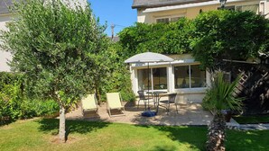 Un patio con mobiliario exterior, una zona de estar cubierta y un césped bien cuidado.