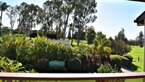 Une vue depuis un balcon donnant sur un jardin bien entretenu, où l’on peut admirer différentes plantes et arbres.