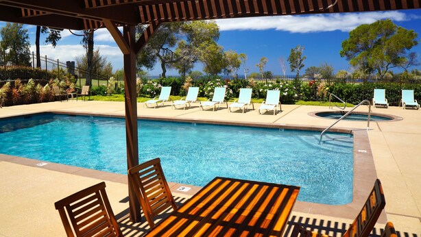 Une piscine avec des chaises longues et un espace de détente abrité.