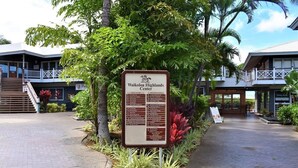 Une enseigne indiquant le « Waikoloa Highlands Center », avec une liste des équipements et un bâtiment en arrière-plan.