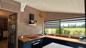 Eine moderne Küche mit einer großen Kochinsel, integriertem Backofen und Blick ins Freie.
