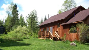 Eine Holzhütte mit einem Balkon, umgeben von einem Rasen und Bäumen.