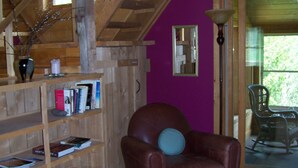 Ein gemütliches Zimmer mit einer Holzregal, einem Ledersessel mit blauem Kissen und einer violetten Wand.